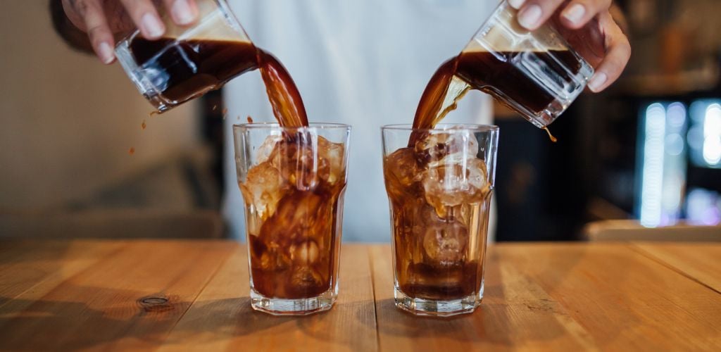 cold brew coffee, espresso coffee being poured over ice in glass tumblers 