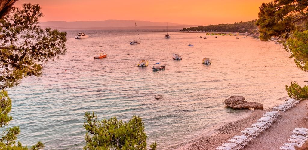 Golden Horn beach in Croatia at dusk, boats line the shore 