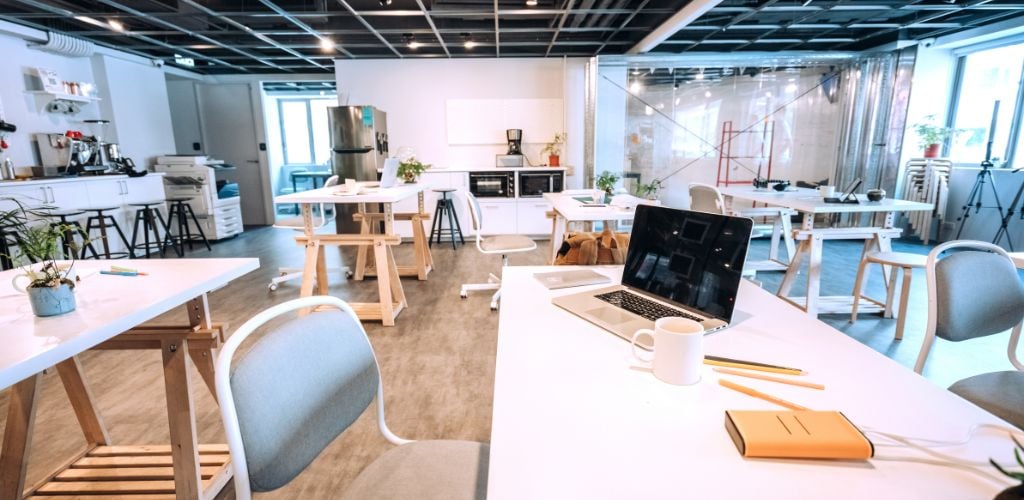 open-planned coworking space with laptop on desk and notebooks